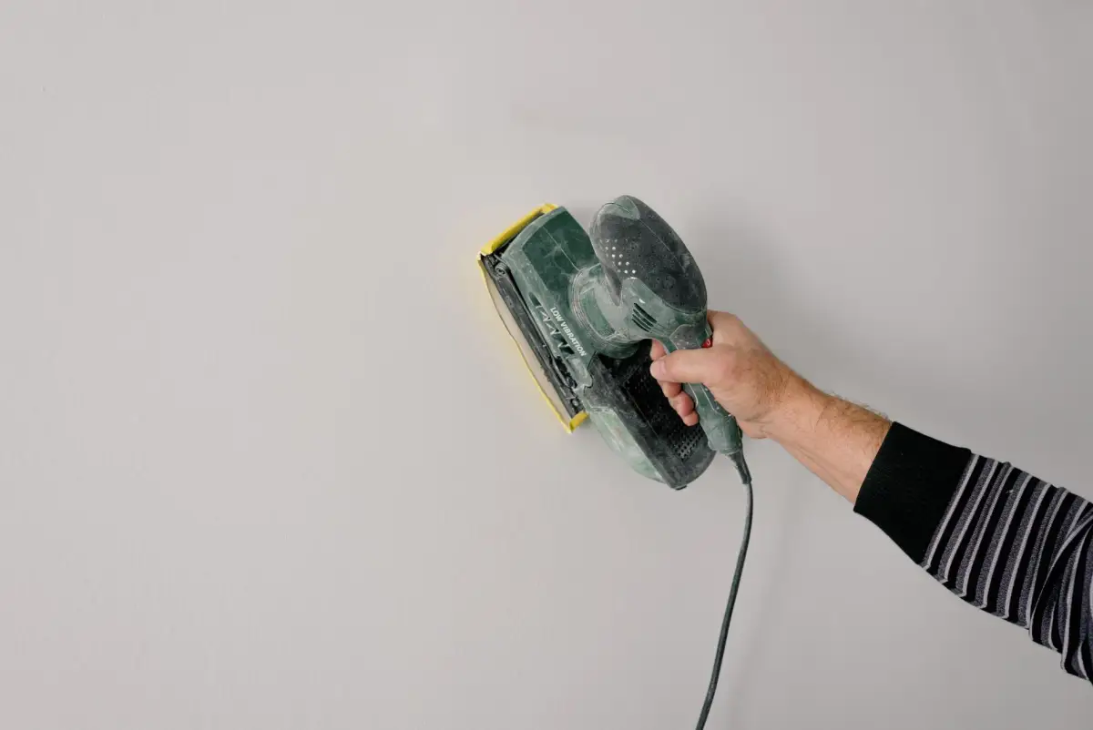 Worker smoothing joint compound during drywall finishing