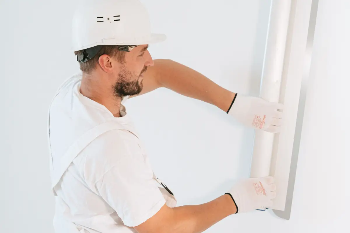 Construction worker installing drywall with gloves and a hardhat