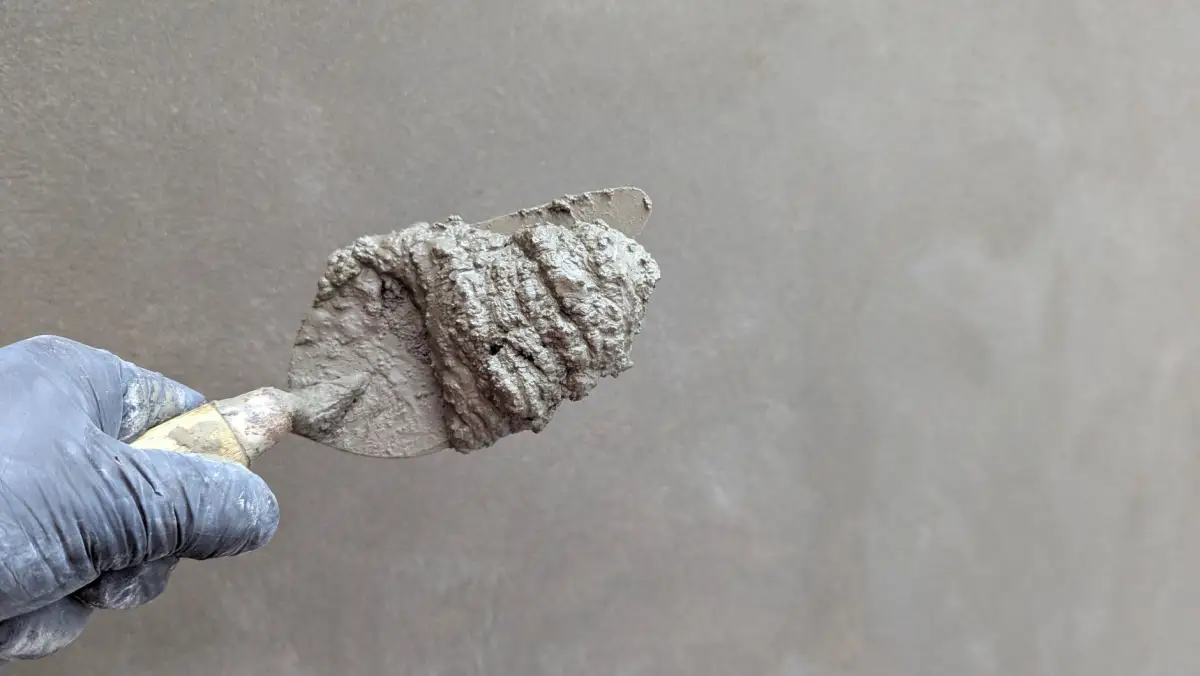Close-up of a trowel applying texture compound to a wall