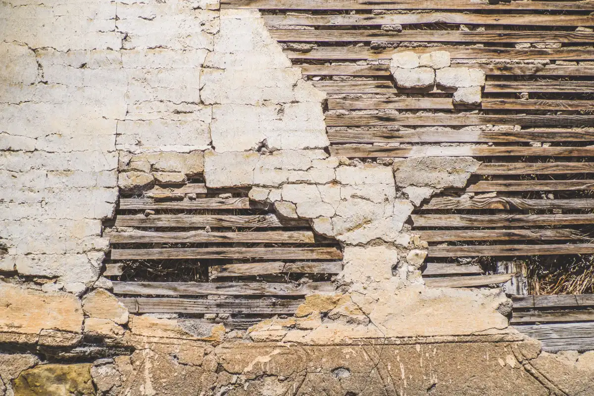 Deteriorating plaster wall revealing the original wood lath beneath