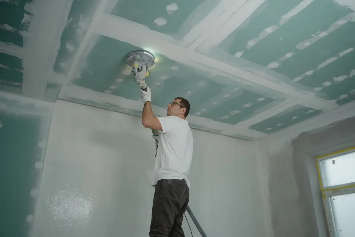 Worker finishing a ceiling to a smooth surface after texture removal
